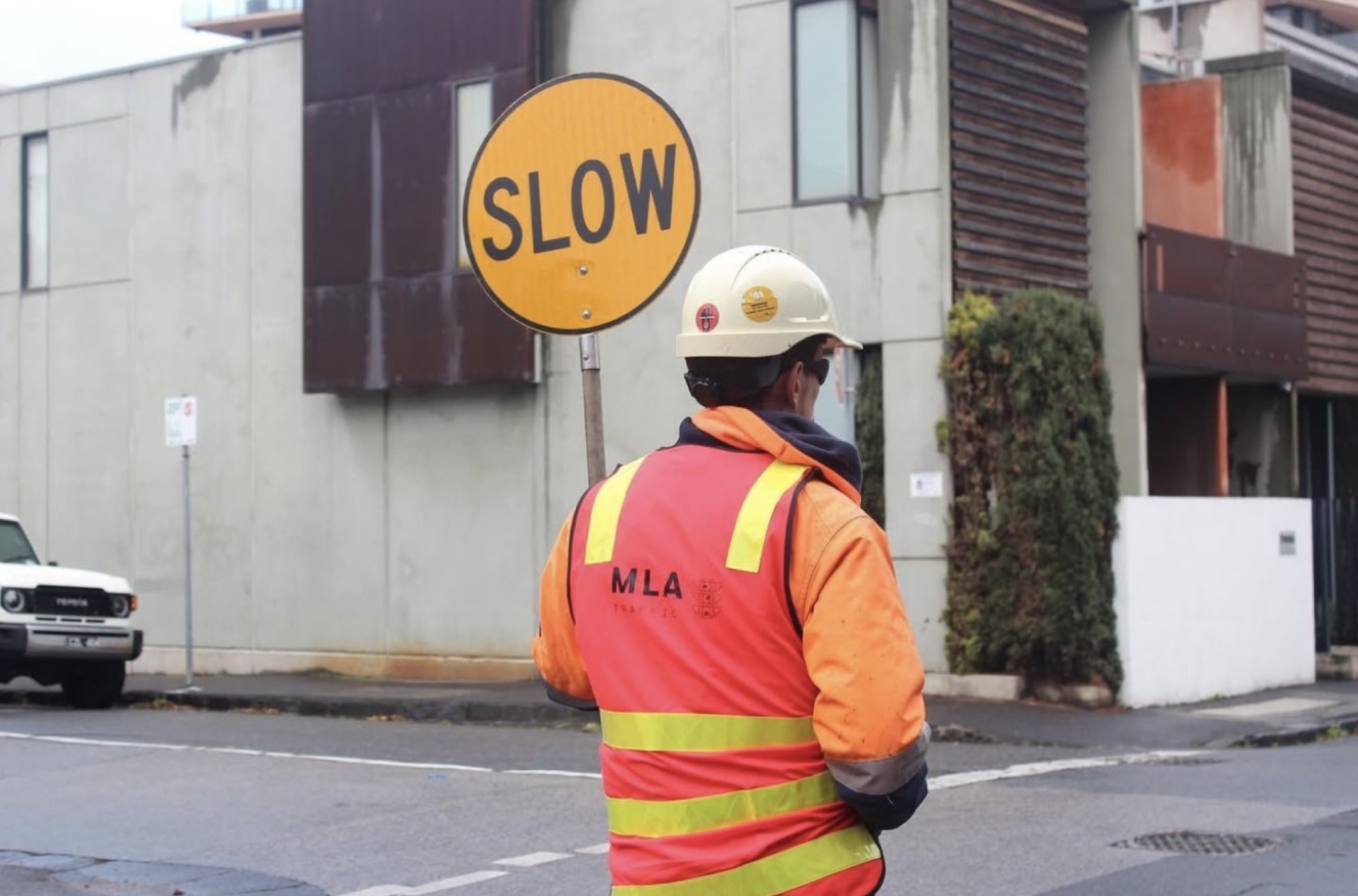 MLA Traffic controller in branded high-vis holding a SLOW sign
